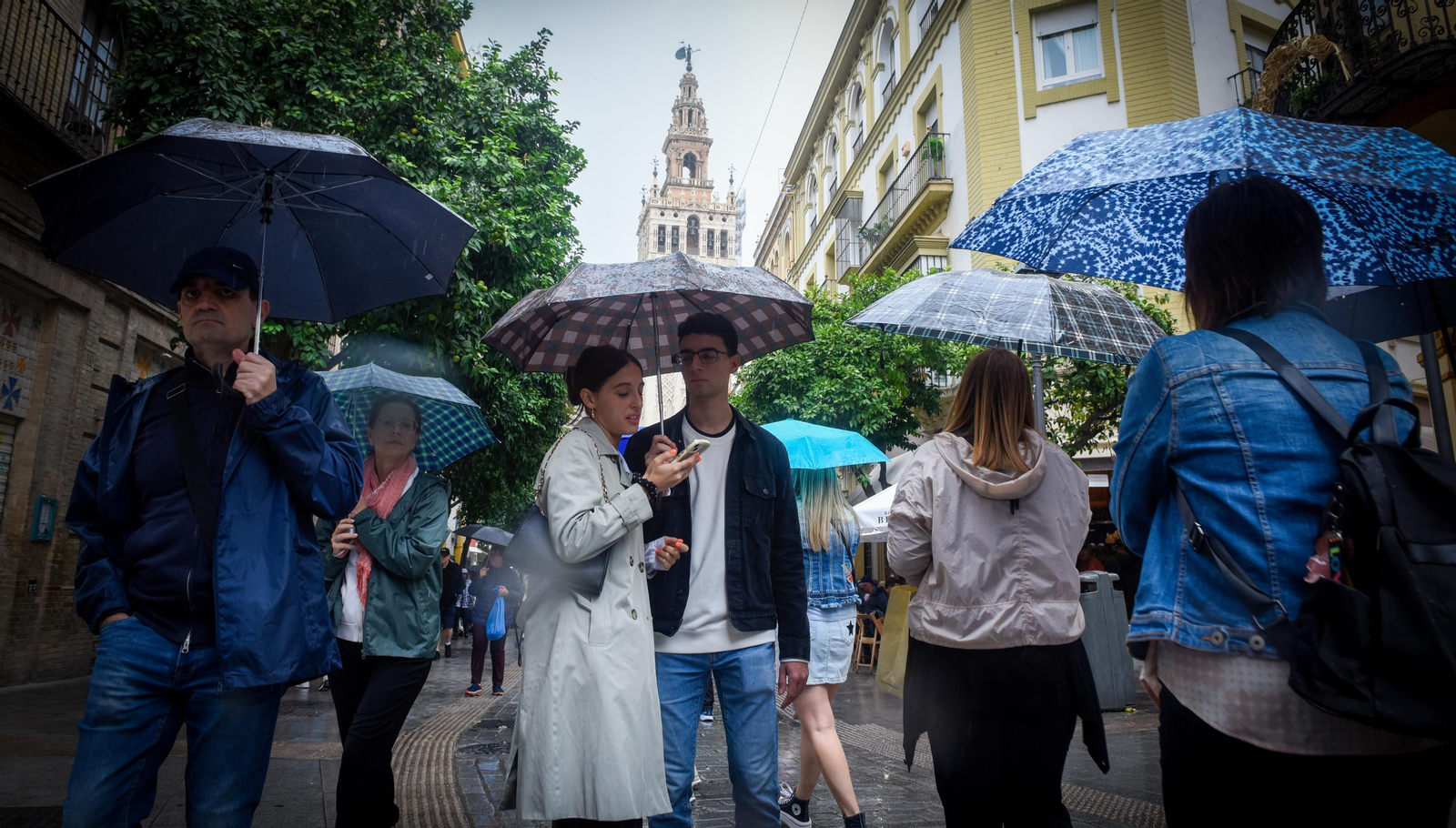 Viandantes ataviados con paraguas en Sevilla.