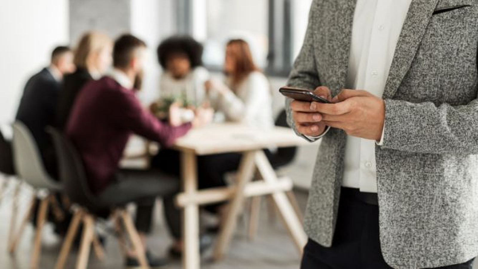 Persona atendiendo al móvil aislada de una reunión.