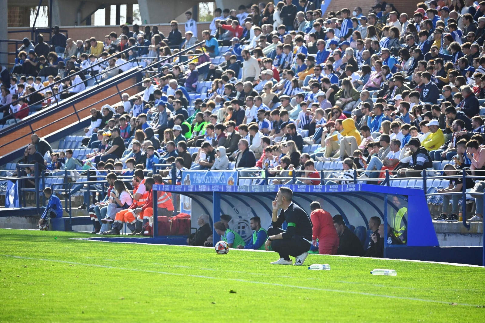 Abel Gómez, agachado, presencia el partido.