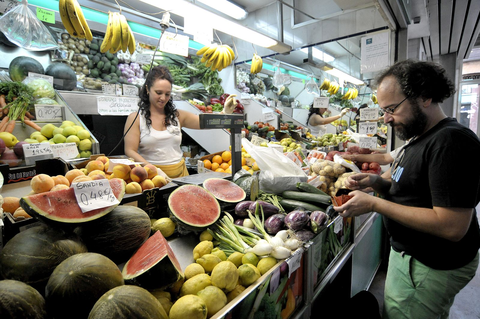 Imagen de archivo de un hombre comprando en un puesto de frutas y verduras