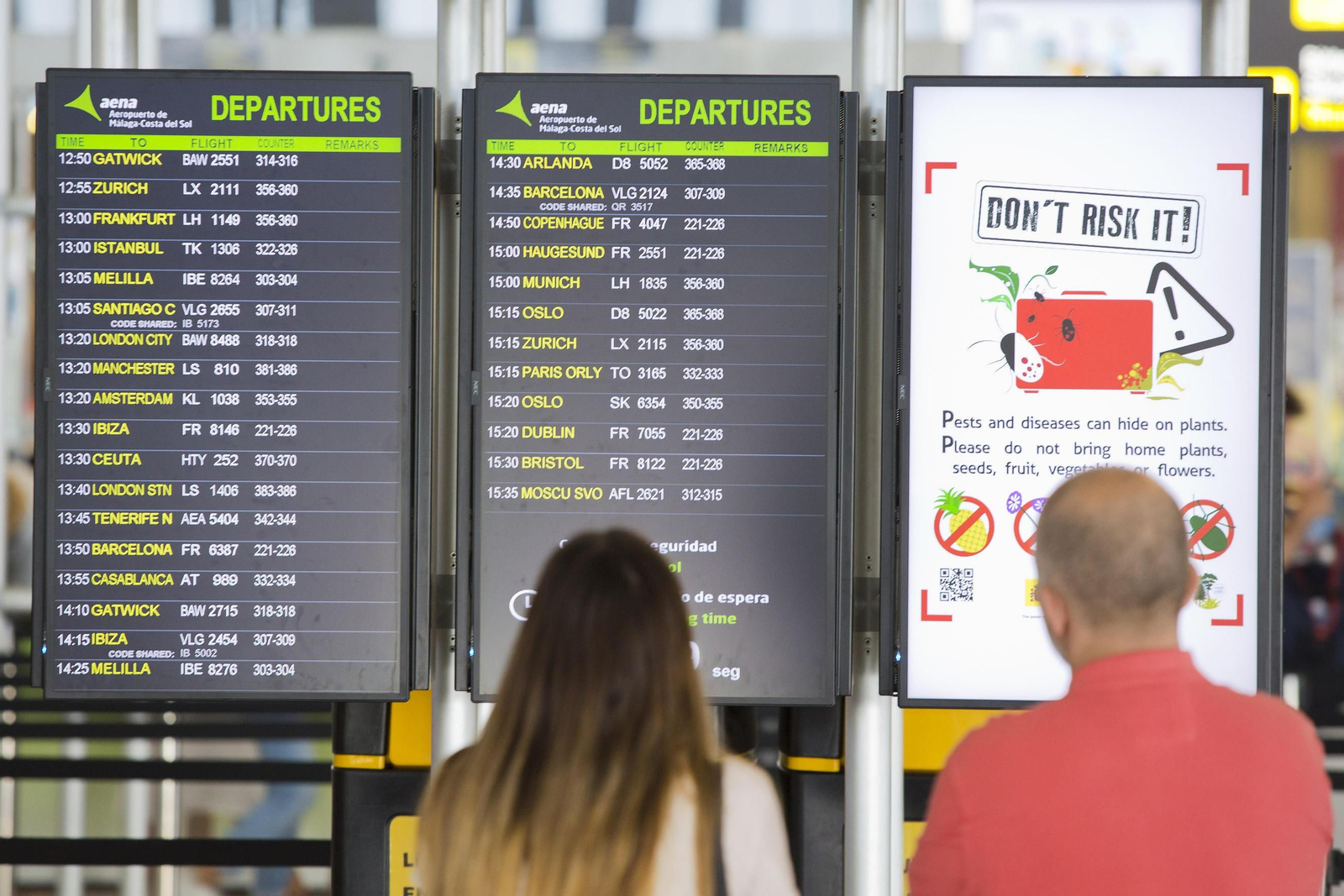 Dos personas miran los paneles de vuelo en el Aeropuerto de Málaga.
