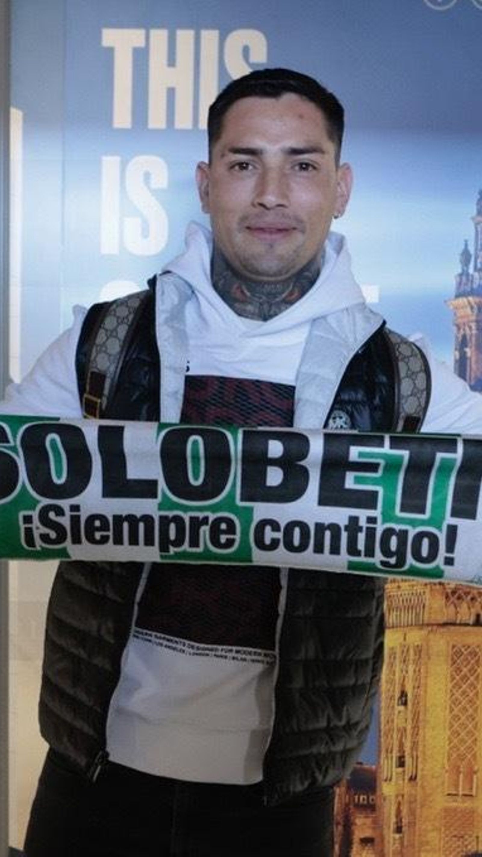 El Chimy Ávila posa con una bufanda del Betis a su llegada al Aeropuerto de San Pablo de la capital hispalense.