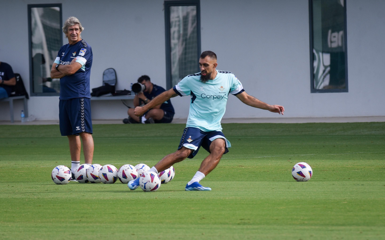 Borja Iglesias golpea el balón, con Pellegrini al fondo, en un entrenamiento en la ciudad deportiva.