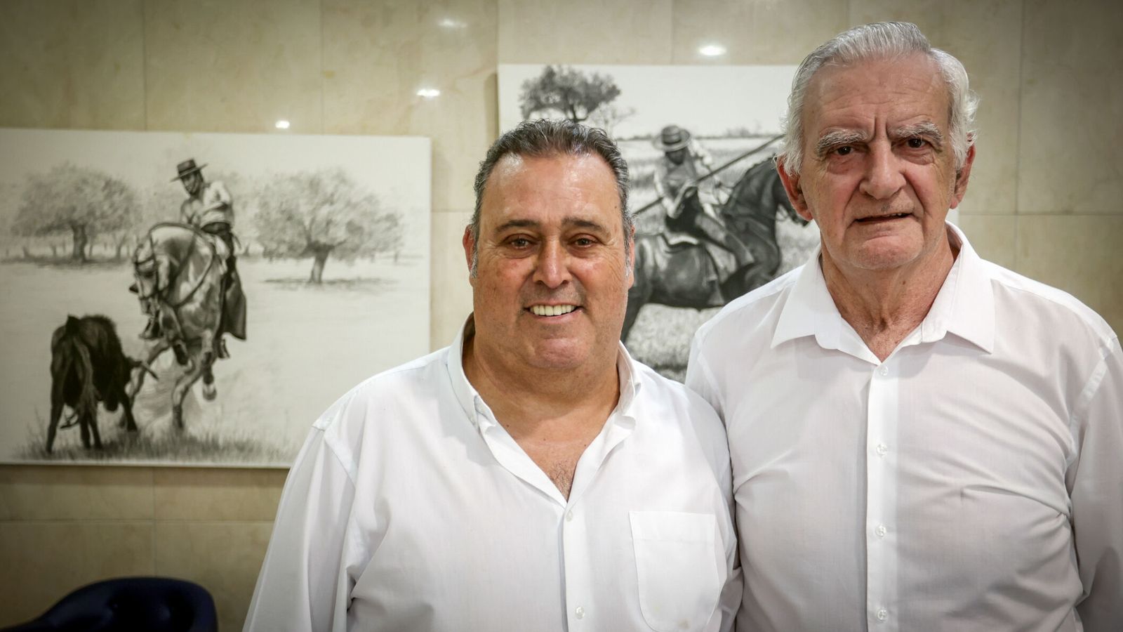 Pepe Olmedo y Juan Gallardo, con dos de los cuadros de los que decoran el local al fondo.
