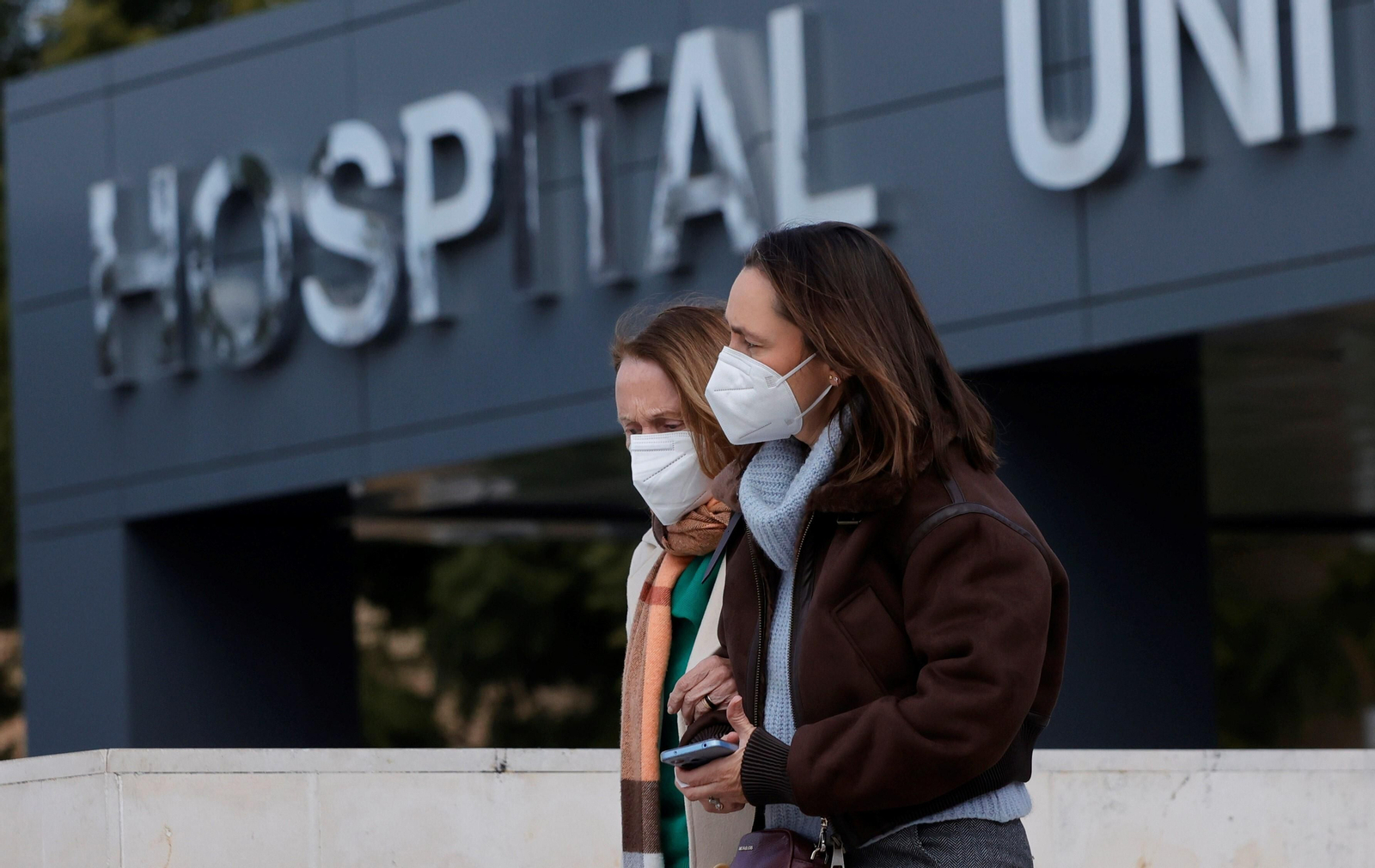 Dos jóvenes con mascarillas salen de un hospital.