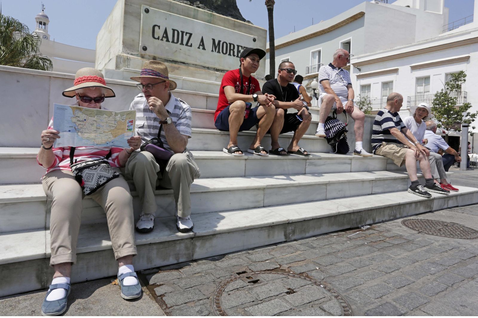 Un grupo de turistas reposa en la escalerilla del monumento a Moret, en la plaza de San Juan de Dios, antes de seguir conociendo la ciudad.