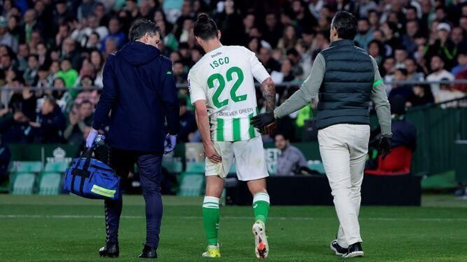 Isco se echa la mano a la parte posterior del muslo izquierdo acompañado por el fisio y el médico.
