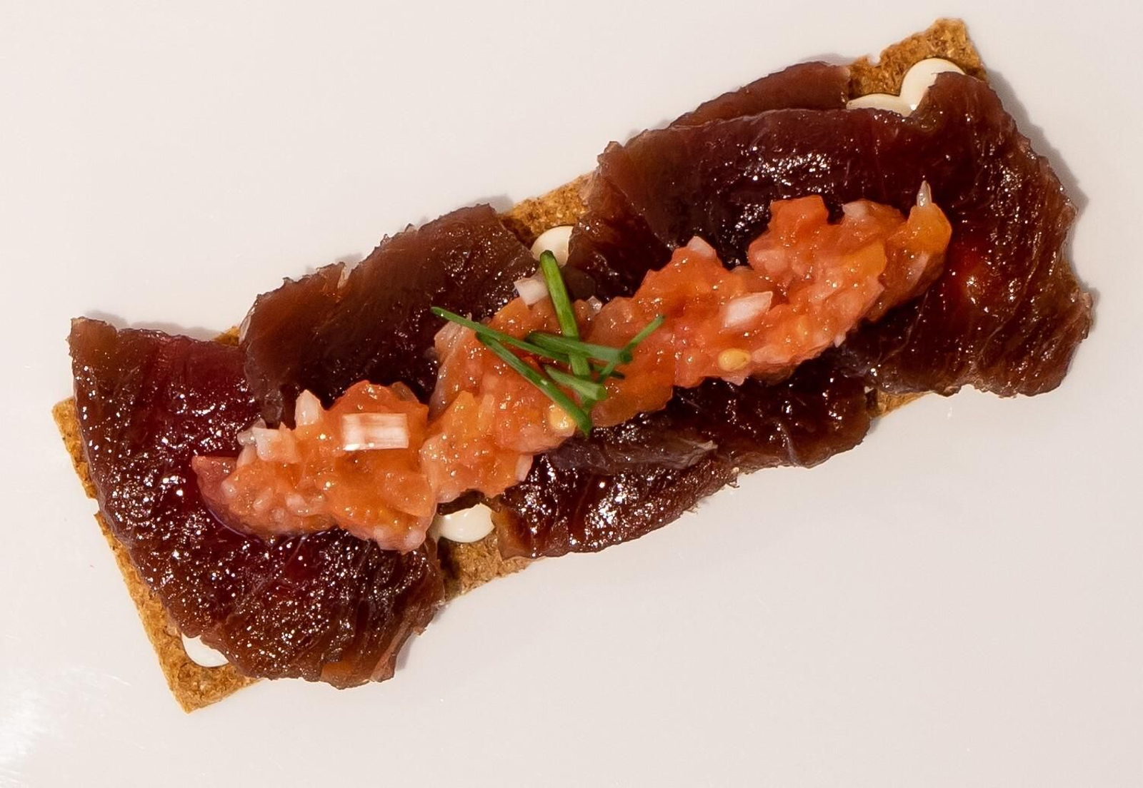 Tosta de atún levemente curado con un toque de ahumado, cremoso de queso y piñones