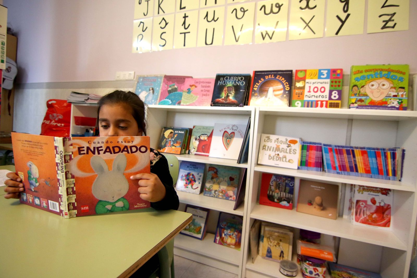 Imagen de archivo de una niña leyendo en una biblioteca.