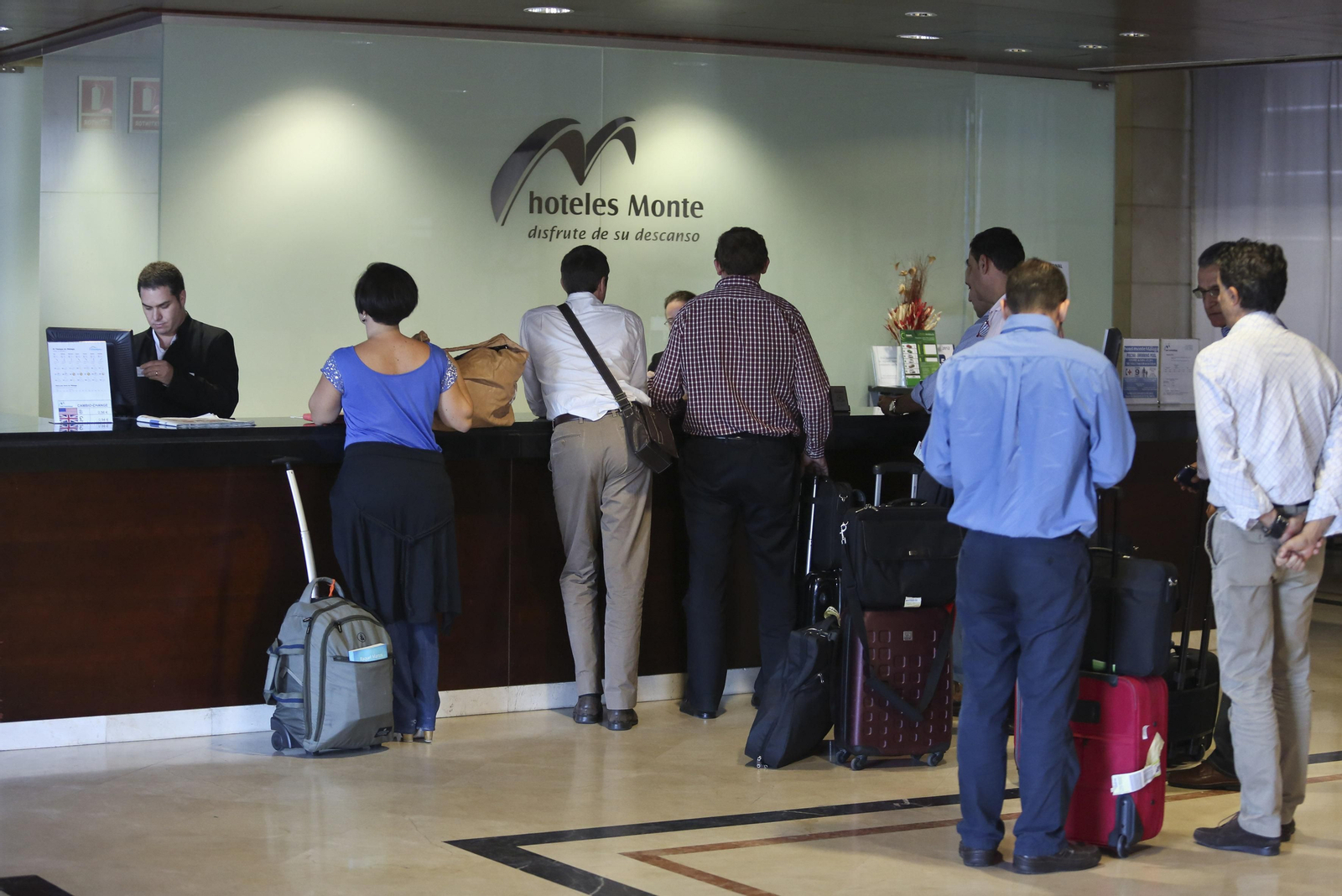 Varios turistas en la recepción de un hotel.