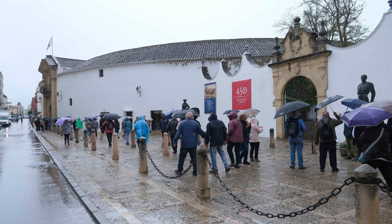 Un grupo de personas se protege de la lluvia junto a la plaza de toros de Ronda este lunes.