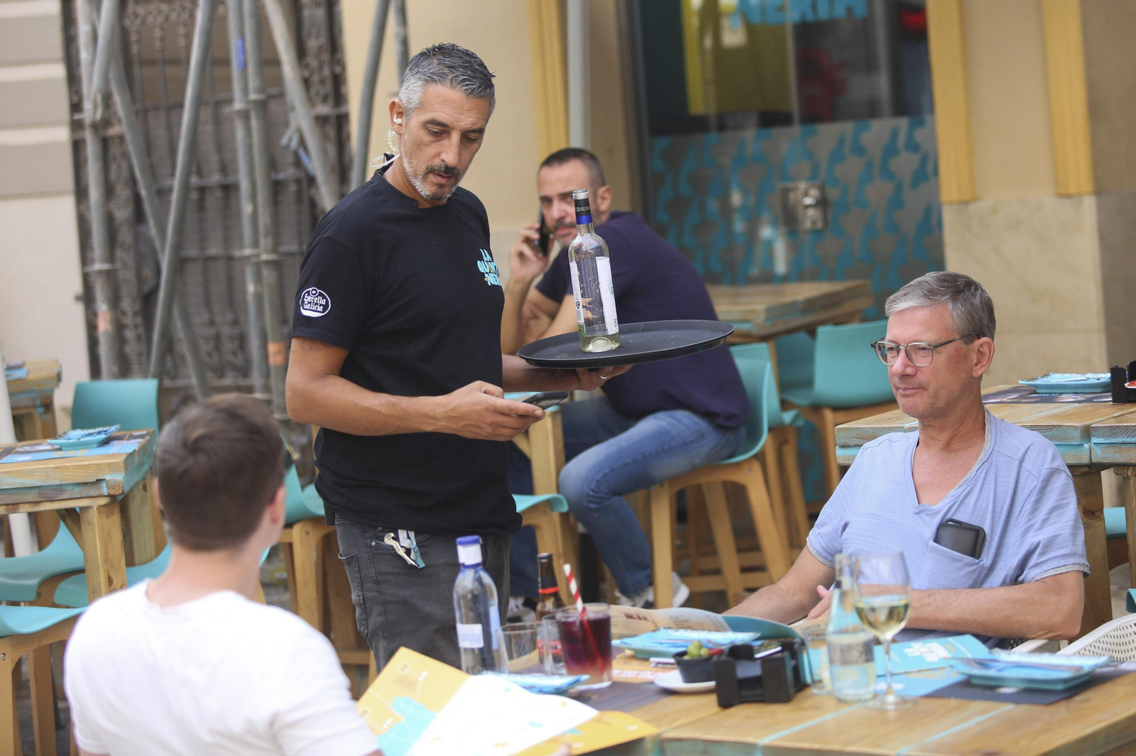 Un camarero sirve a unos clientes en un restaurante del Centro Histórico de Málaga.