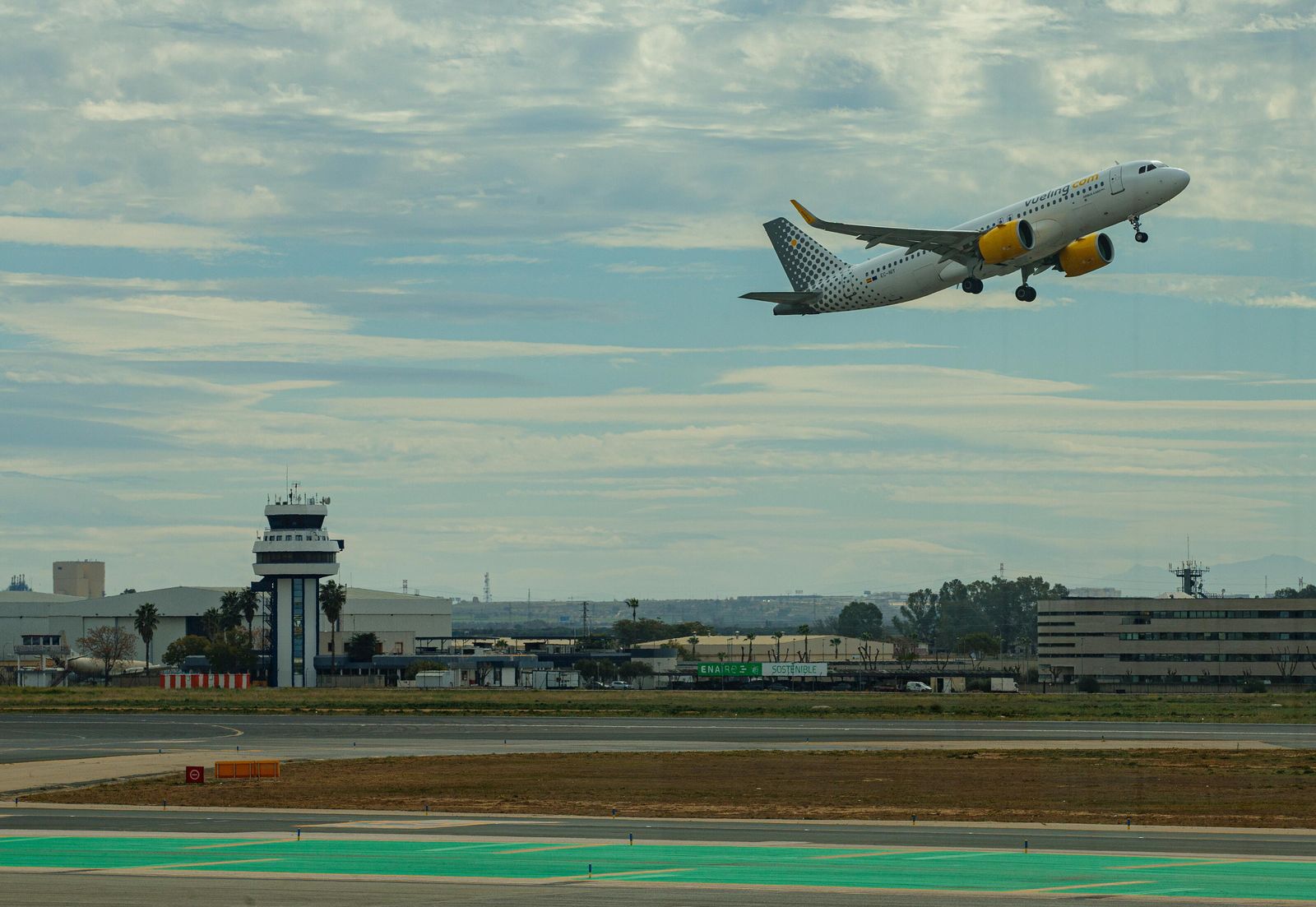 Un avión tras despegar junto a la torre de  control del Aeropuerto  de  Sevilla.