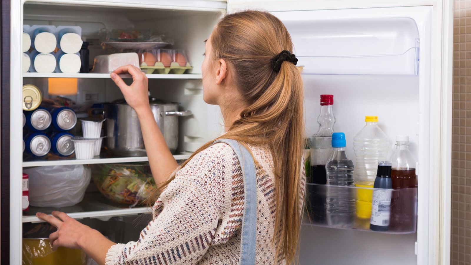 Una chica echa un vistazo a lo que contiene el interior de su frigorífico