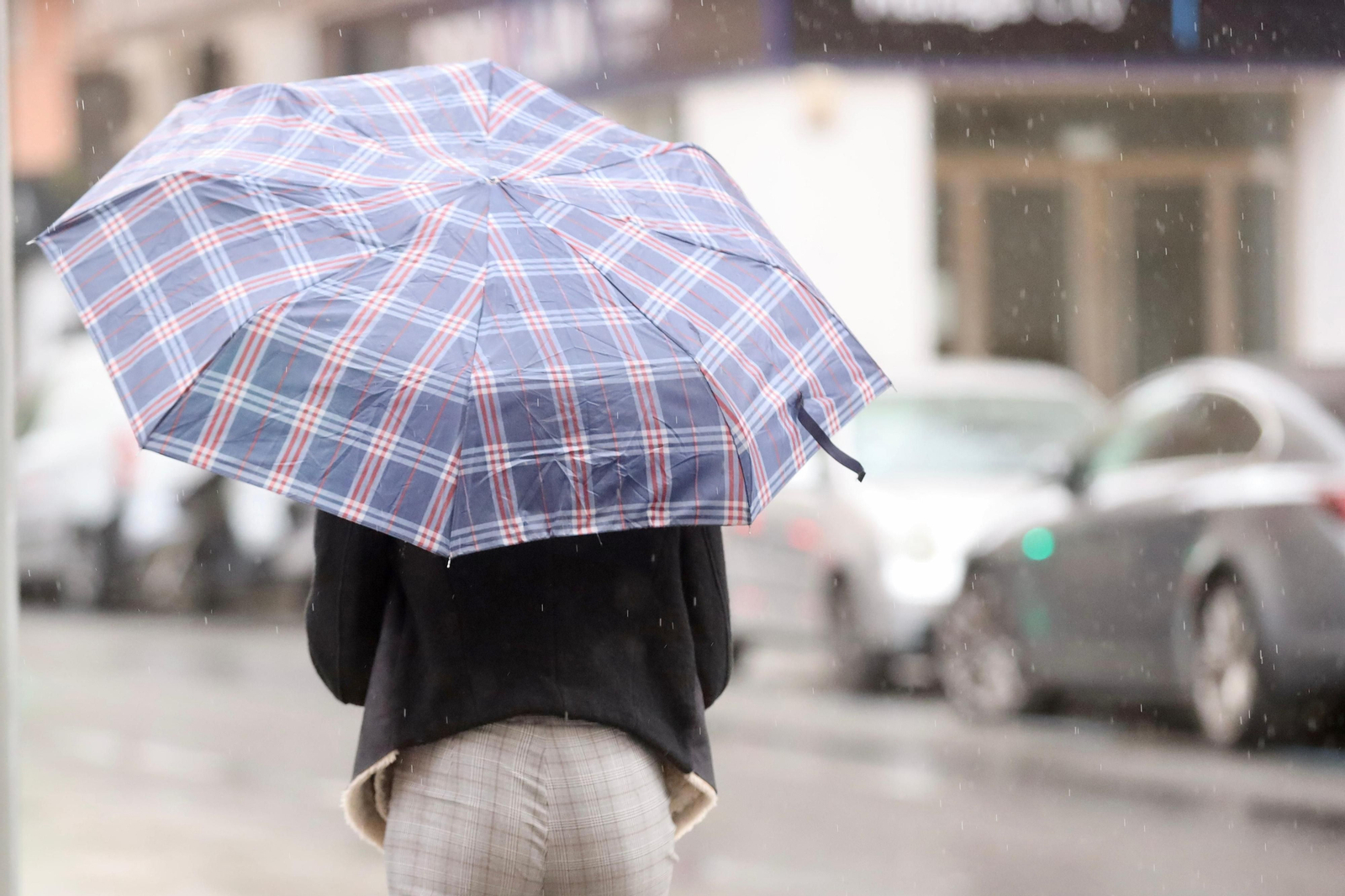 Una mujer se protege de la lluvia este domingo en Málaga.