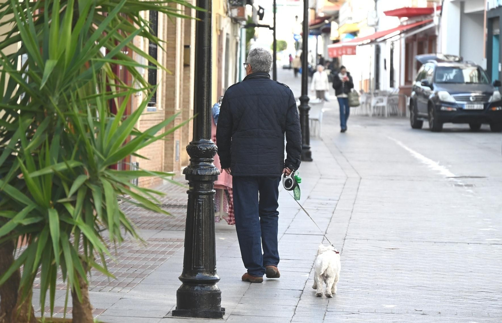 Un vecino paseando a su mascota con bolsas para la recogida de excrementos.