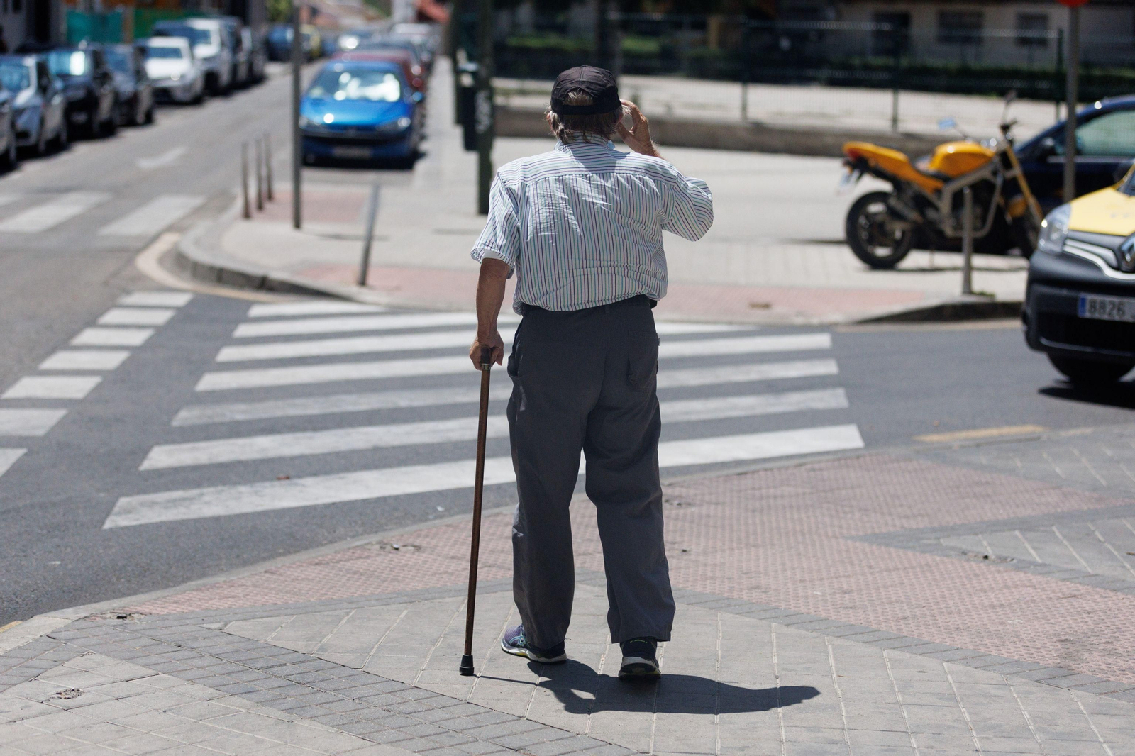 Un hombre de avanzada edad avanza hacia un paso de peatones